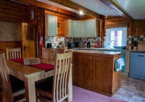cocina con mesa de madera con sillas y fregadero en Rona en Duirinish