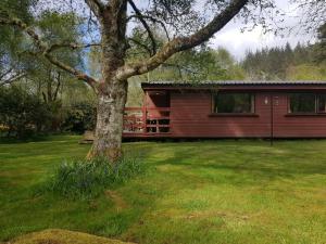 una casa roja con un árbol en el patio en Rona en Duirinish
