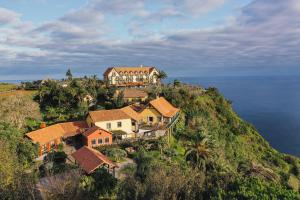 a house on top of a hill next to the ocean at Hotel Quinta Do Furao in Santana