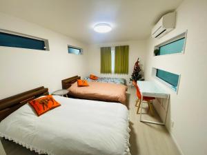 a bedroom with two beds and a desk and windows at Love House in Osaka