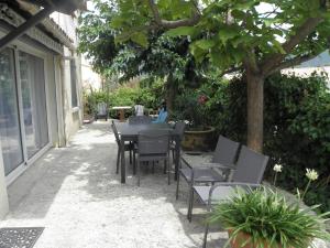 尼永斯的住宿－Chez Pascaline，树下带桌椅的天井