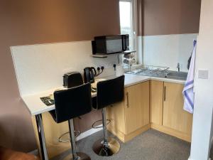 a kitchen with a counter with two chairs and a microwave at Vale View in Denbigh