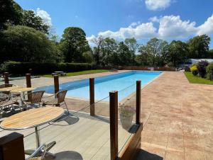a pool with a wooden deck and a table and chairs at SNOWDONIA COTTAGE Glan Gwna Holiday Park in Caernarfon