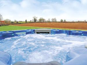 a hot tub filled with water next to a field at Heckingham Manor in Loddon