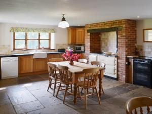 a kitchen with a table and chairs and a brick wall at Heckingham Manor in Loddon