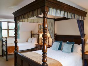two beds in a bedroom with two canopy beds at Heckingham Manor in Loddon