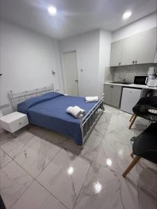 a bedroom with a bed with blue sheets and a kitchen at Jacks Apartment in Paphos City