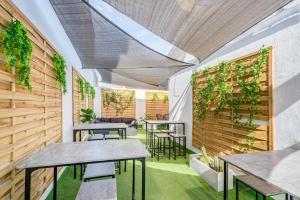a room with tables and chairs and a wall with plants at Casa Barcelo Camp Nou Barcelona in Hospitalet de Llobregat
