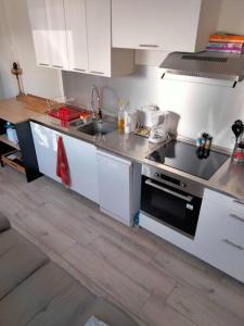 uma cozinha com armários brancos e um forno com placa de fogão em Aubagne 3 chambre au petit pin vert em Aubagne