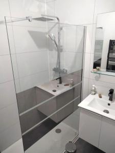 uma casa de banho branca com um chuveiro e um lavatório. em Aubagne 3 chambre au petit pin vert em Aubagne