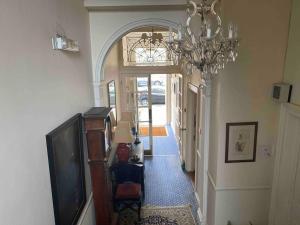 a hallway with a television and a chandelier at Great Pulteney St. Maisonette (parking) in Bath
