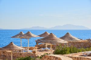 un grupo de sombrillas y sillas de paja en una playa en Dreams Vacation Resort - Sharm El Sheikh en Sharm El Sheikh