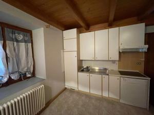 eine Küche mit weißen Schränken und einem Waschbecken in der Unterkunft Casa Streberi in Castelfondo