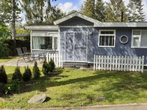 a small blue house with a white fence in a yard at Knus buitenhuisje aan de Veluwe in Putten