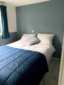 a bedroom with a bed with a blue blanket on it at Knus buitenhuisje aan de Veluwe in Putten