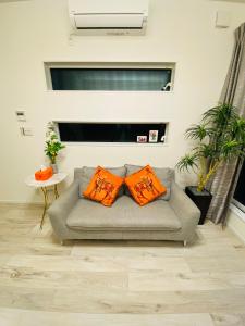 a living room with a couch with two orange pillows at Love House in Osaka