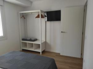 1 dormitorio blanco con 1 cama y TV en Apartamentos turísticos Demar en O Grove