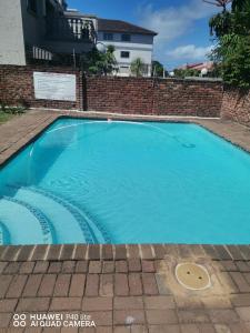 a blue swimming pool with a brick wall at Uvongo Sea Scapes Holiday Apartment in Margate