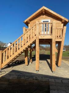 a large wooden dog house with a roof at Hoogte Huisje Schotland in Swalmen