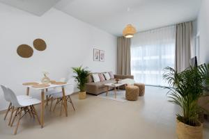 uma sala de estar com um sofá, uma mesa e cadeiras em Waves Holiday Home - Chic Apartment With Dubai Skyline Views no Dubai