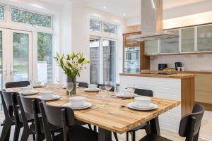 a kitchen and dining room with a wooden table and chairs at Pillo Rooms - Spacious 4 Bedroom Detached House close to Heaton Park in Manchester