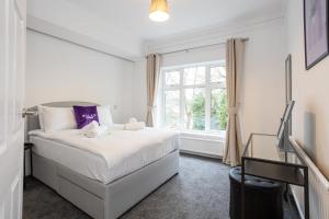 a white bedroom with a bed and a window at Pillo Rooms - Spacious 4 Bedroom Detached House close to Heaton Park in Manchester