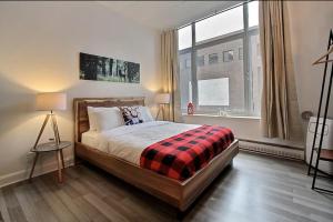 1 dormitorio con cama y ventana grande en INITIAL - LOFT FORESTIER - Centre-Ville de Québec, en Quebec