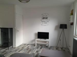 a living room with a television on a white wall at Agréable maison proche de la côte de granit rose in Lannion