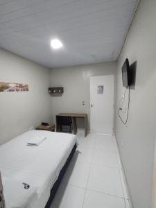 a room with a bed and a desk and a television at Hotel Resende in Imperatriz