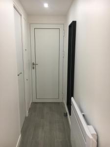 einen Flur mit weißer Tür und Fliesenboden in der Unterkunft Appartement Cœur de Ville - Saint Germain en Laye in Saint-Germain-en-Laye