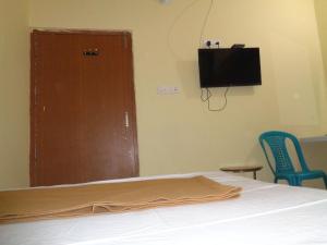 um quarto com uma cama e uma televisão de ecrã plano em Ganesh Residency em Cuttack
