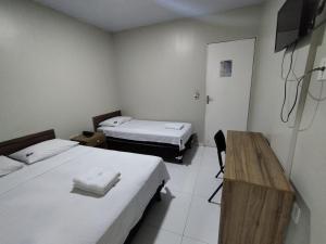 a room with two beds and a table and a desk at Hotel Resende in Imperatriz