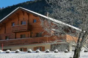 a log cabin in the snow with a tree at Lélex, appartement "HERMINE" dans chalet, piscine couverte in Lélex