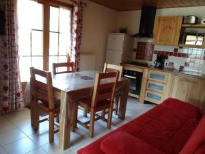 a kitchen with a wooden table and chairs and a couch at Lélex, appartement "HERMINE" dans chalet, piscine couverte in Lélex