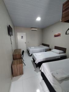 Zimmer mit 3 Betten und einem Schreibtisch. in der Unterkunft Hotel Resende in Imperatriz