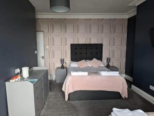 a bedroom with a large bed with pink sheets at Min y Mor Hotel in Barmouth