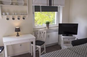 Zimmer mit einem Schreibtisch, einem TV und einem Fenster in der Unterkunft Apartmenthaus Frauenpreis FeWo 61 in Cuxhaven