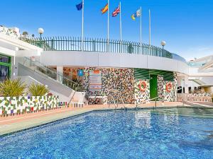 une piscine en face d'un bâtiment arborant des drapeaux dans l'établissement Porlamar, à Puerto Rico
