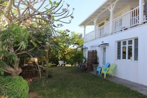 un patio trasero de una casa blanca con mesa y sillas en Le Colibri et le Frangipanier en La Trinité