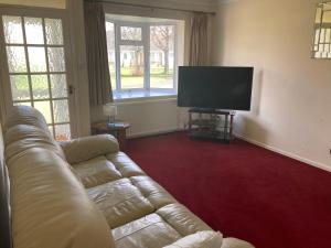 ein Wohnzimmer mit einem Sofa und einem Flachbild-TV in der Unterkunft bungalow on the south coast & new forest in Lymington