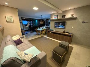 ein Wohnzimmer mit einem Sofa und einem TV in der Unterkunft RIVIERA MANHATTAN - Luxuoso 4 quartos, varanda Gourmet in Aquiraz
