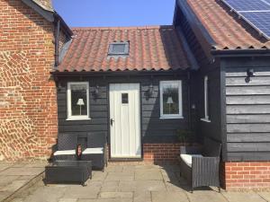 a black house with two chairs and a white door at The Granary in Stuston