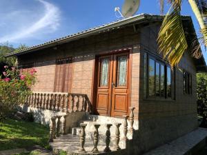 mały dom z drewnianymi drzwiami i werandą w obiekcie Sítio Solar di Stella w mieście Itatiaia