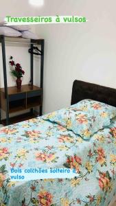 uma cama com um edredão floral num quarto em Lindo apto com piscina em Praia Grande - QX01H em Solemar
