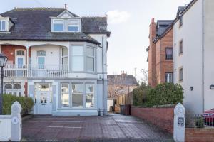 een wit huis met een veranda in een straat bij The Chymes Holiday Flats in Lytham St Annes