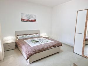 a white bedroom with a bed and a mirror at La vecchia sartoria in Mazzarino