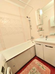 y baño con bañera blanca, lavabo y espejo. en HappyTerra, район ТРЦ "АДК", en Almaty
