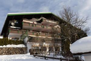 a large house with a balcony in the snow at Hotel Sonnleiten in Reit im Winkl