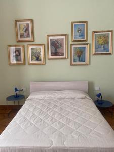 ミラノにあるGambara Apartmentの白いベッドと壁に4枚の絵が飾られたベッドルーム1室