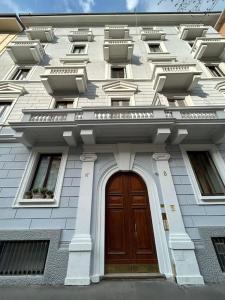 biały budynek z drewnianymi drzwiami i oknami w obiekcie Gambara Apartment w Mediolanie
